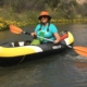 Woman with hat on in an inflatable kayak, smiling