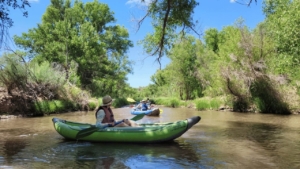 Woman in green inflatable kayak on the Verde River, side view