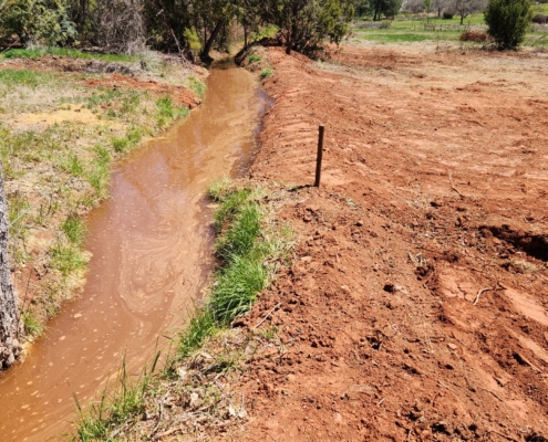 repaired irrigation ditch, now flowing efficiently with water