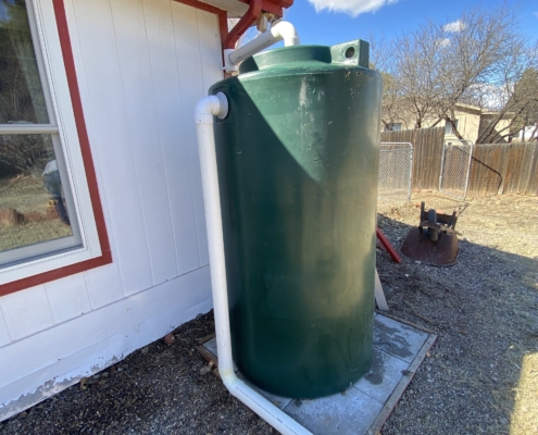 A large rainwater harvesting tank connected to a gutter's downspout